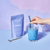 Iced Latte made with Blume Superfood Blue Lavender Blend with a hand holding a blue glass straw